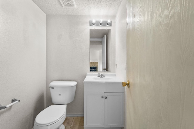 bathroom featuring tile patterned floors, vanity, toilet, and a textured ceiling