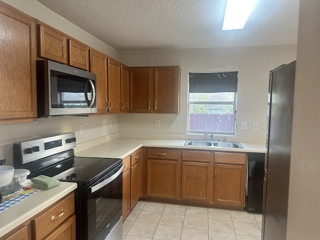 kitchen featuring appliances with stainless steel finishes, sink, light tile patterned floors, and a textured ceiling