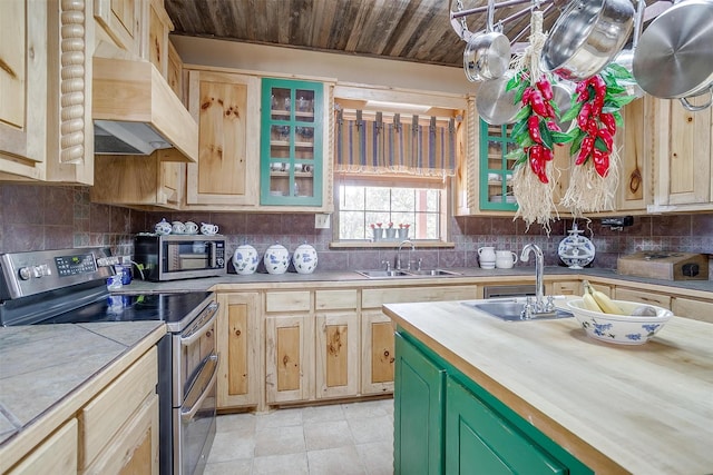 kitchen featuring butcher block counters, sink, green cabinetry, premium range hood, and appliances with stainless steel finishes