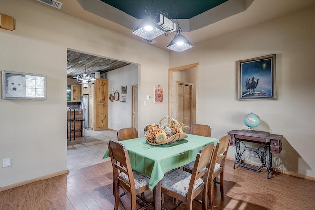 dining room with a tray ceiling and wood-type flooring