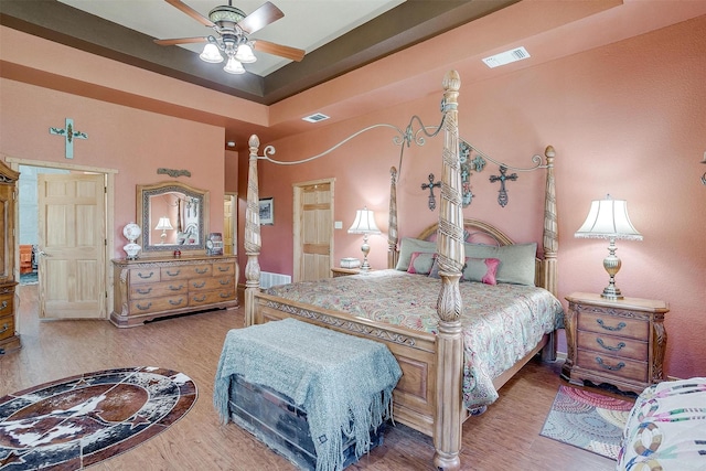 bedroom with a tray ceiling, ceiling fan, and hardwood / wood-style flooring