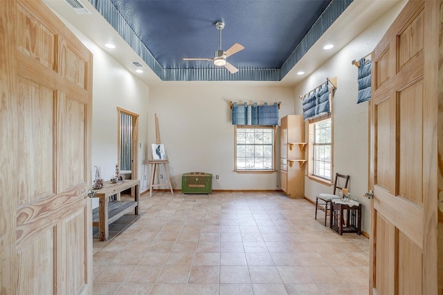 living area with light tile patterned floors, a tray ceiling, and ceiling fan