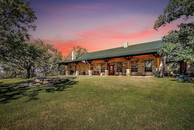 back house at dusk featuring a yard