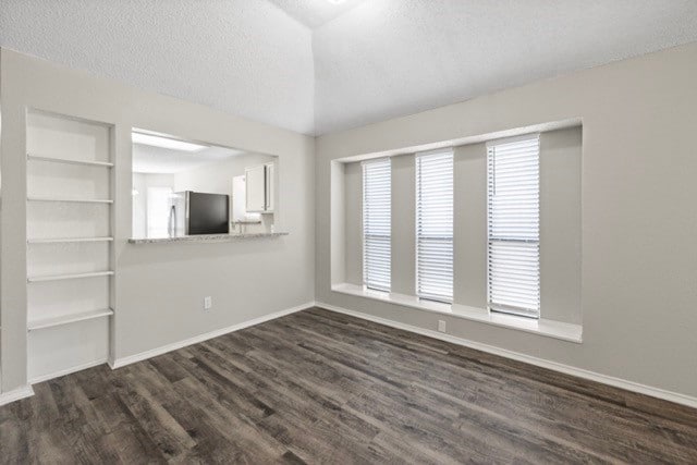 unfurnished room with built in shelves, a textured ceiling, and dark hardwood / wood-style flooring