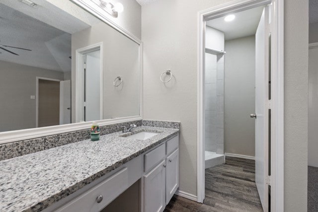 bathroom with vanity, a shower, hardwood / wood-style flooring, and ceiling fan