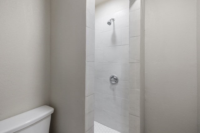 bathroom featuring a tile shower and toilet