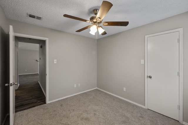 unfurnished bedroom featuring ceiling fan, carpet flooring, and a textured ceiling