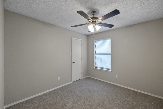 carpeted spare room with ceiling fan and a textured ceiling