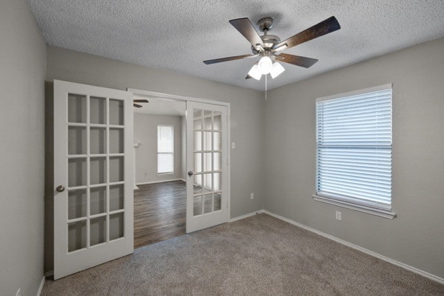 empty room featuring french doors, ceiling fan, a healthy amount of sunlight, and carpet