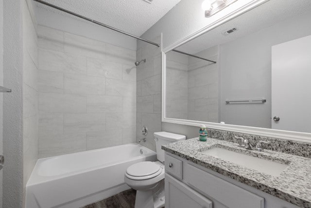 full bathroom with toilet, wood-type flooring, tiled shower / bath, vanity, and a textured ceiling