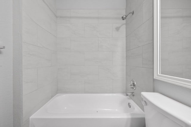 bathroom with tiled shower / bath combo and toilet