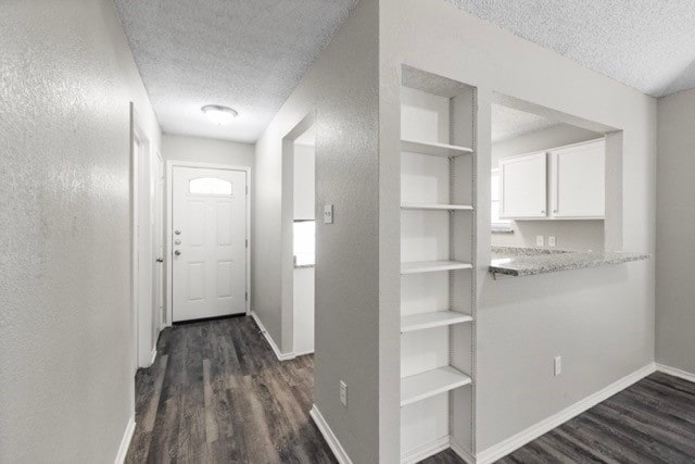 hallway with dark hardwood / wood-style floors, a textured ceiling, and built in features