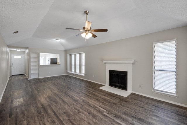 unfurnished living room featuring lofted ceiling, dark hardwood / wood-style floors, plenty of natural light, and ceiling fan