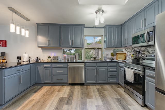 kitchen featuring pendant lighting, sink, stainless steel appliances, and light hardwood / wood-style floors