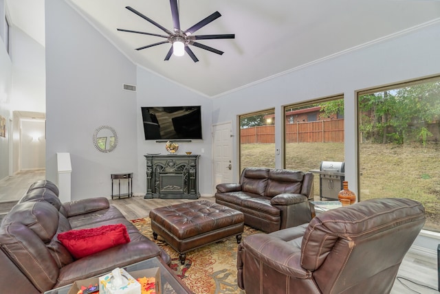 living room with ceiling fan, light wood-type flooring, crown molding, and high vaulted ceiling