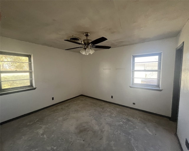 empty room with concrete floors, a healthy amount of sunlight, and ceiling fan