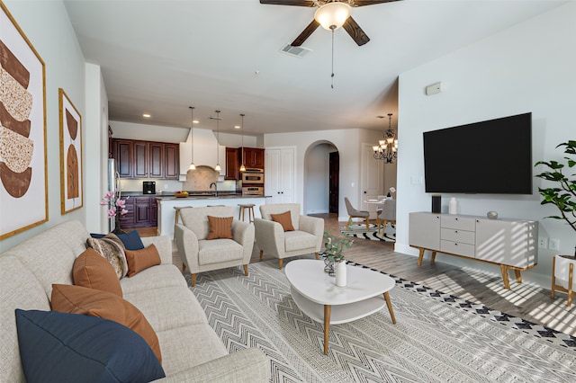 living room with light hardwood / wood-style floors and ceiling fan with notable chandelier