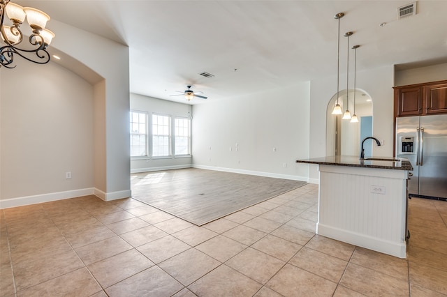 kitchen with light hardwood / wood-style flooring, stainless steel refrigerator with ice dispenser, dark stone counters, pendant lighting, and ceiling fan with notable chandelier