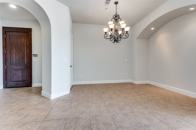 spare room featuring a notable chandelier and light tile patterned floors