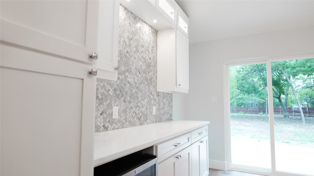 kitchen with wine cooler, white cabinetry, and backsplash