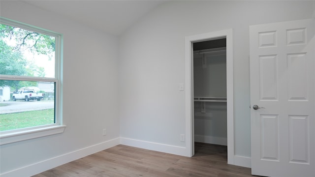 unfurnished bedroom with lofted ceiling and light hardwood / wood-style flooring