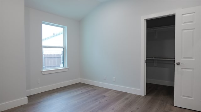 unfurnished bedroom with a closet, lofted ceiling, and hardwood / wood-style floors