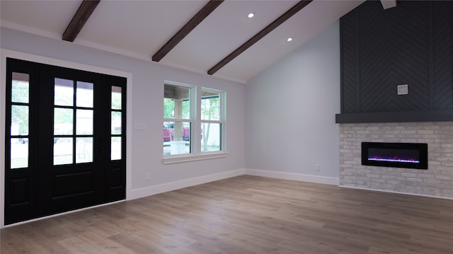 foyer entrance featuring a fireplace, lofted ceiling with beams, and light wood-type flooring