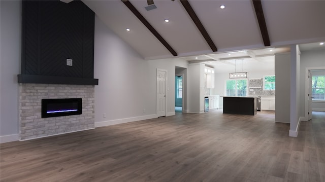 unfurnished living room with hardwood / wood-style flooring, beamed ceiling, high vaulted ceiling, and a fireplace