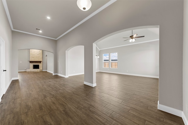 unfurnished living room with ornamental molding, a stone fireplace, dark hardwood / wood-style floors, and ceiling fan