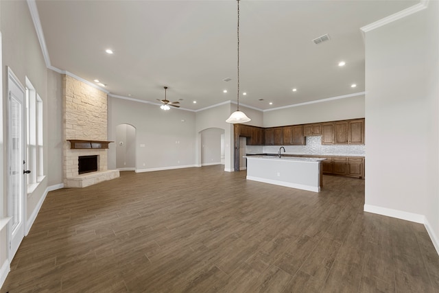 unfurnished living room with ceiling fan, dark hardwood / wood-style flooring, a fireplace, crown molding, and sink