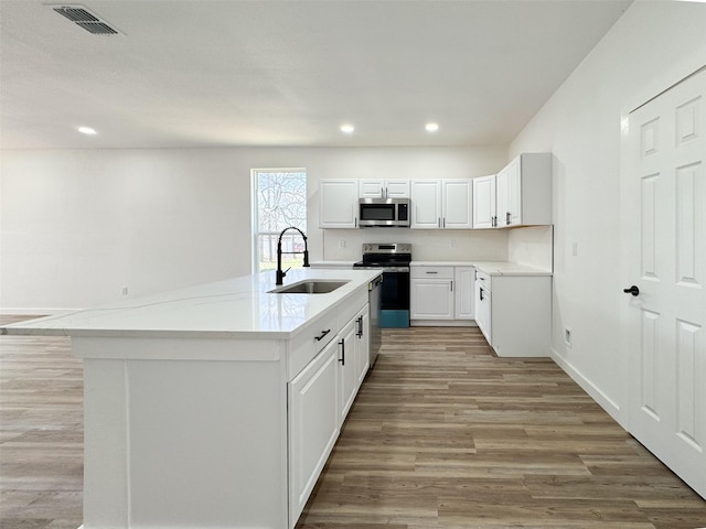 kitchen with visible vents, light wood-style flooring, a sink, white cabinetry, and appliances with stainless steel finishes