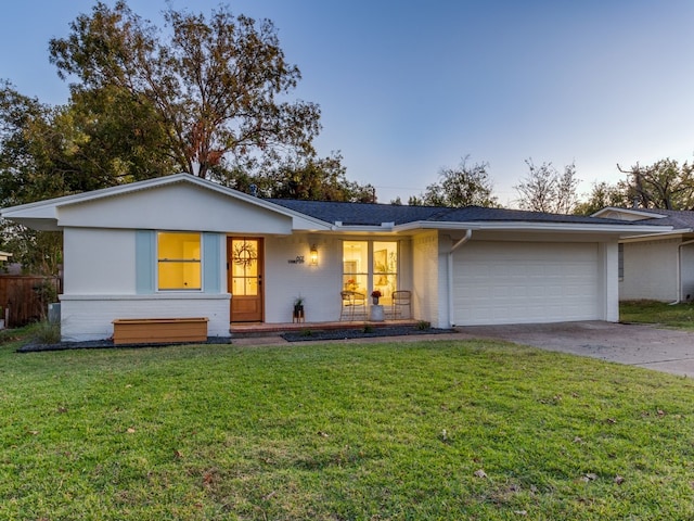 single story home with a yard, covered porch, and a garage