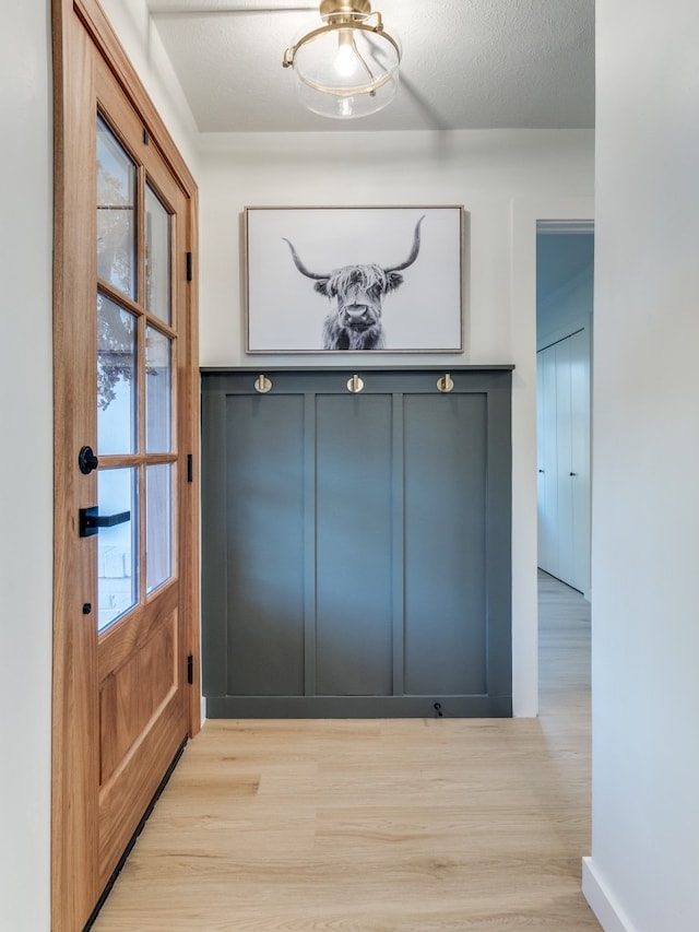 doorway featuring light hardwood / wood-style flooring and a textured ceiling