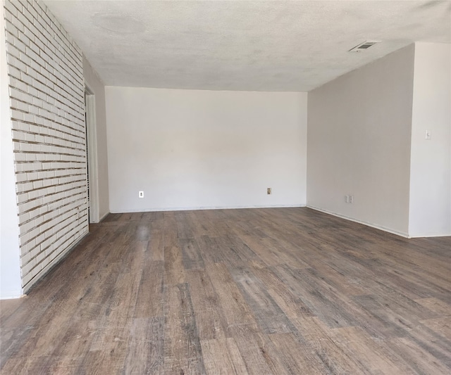 empty room featuring a textured ceiling and dark hardwood / wood-style flooring