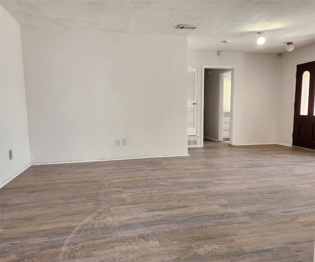 empty room featuring a textured ceiling and dark hardwood / wood-style floors