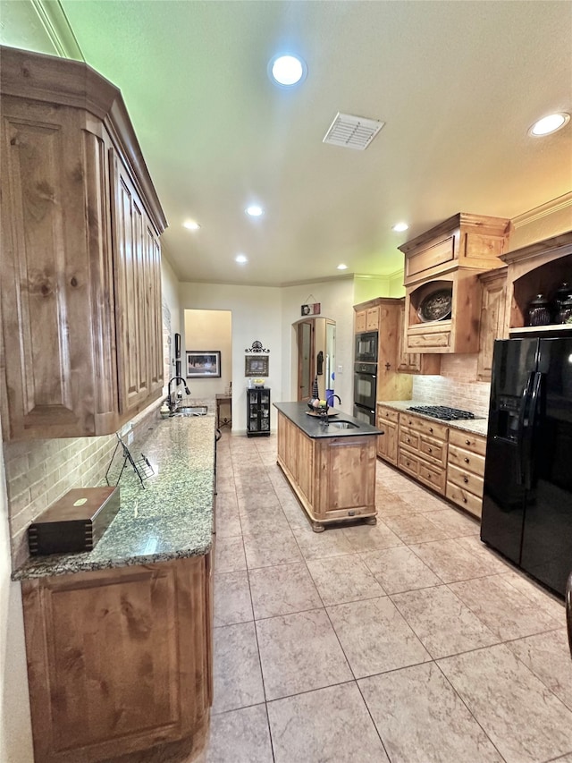 kitchen featuring tasteful backsplash, black appliances, sink, a center island, and dark stone counters