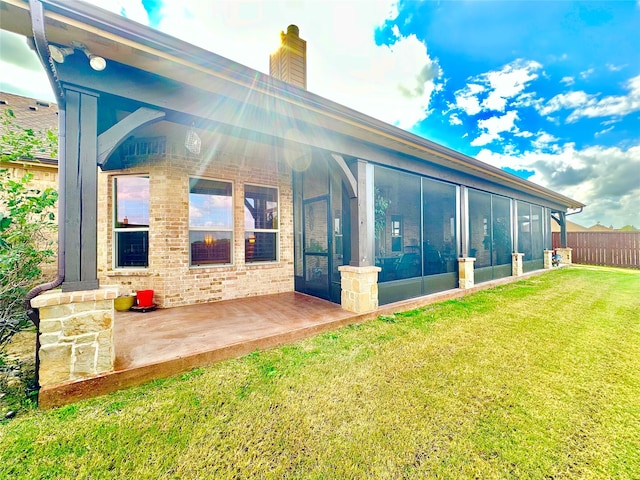 rear view of house featuring a yard and a sunroom