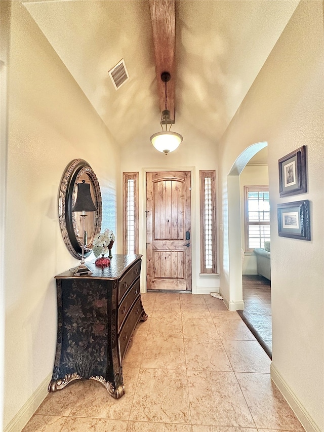 entrance foyer featuring lofted ceiling, a textured ceiling, and light tile patterned flooring