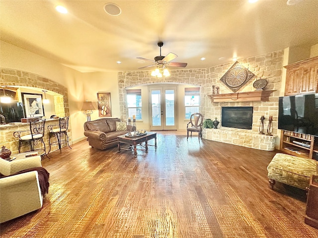 living room featuring hardwood / wood-style floors, french doors, a stone fireplace, and ceiling fan