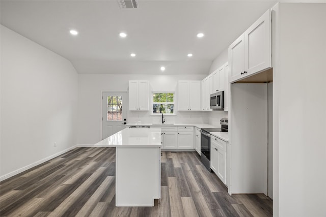 kitchen with white cabinetry, sink, dark hardwood / wood-style flooring, a kitchen island, and appliances with stainless steel finishes