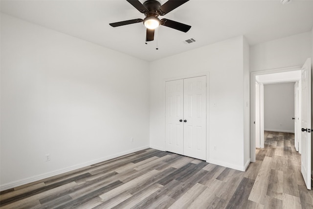 unfurnished bedroom featuring ceiling fan, a closet, and light hardwood / wood-style floors