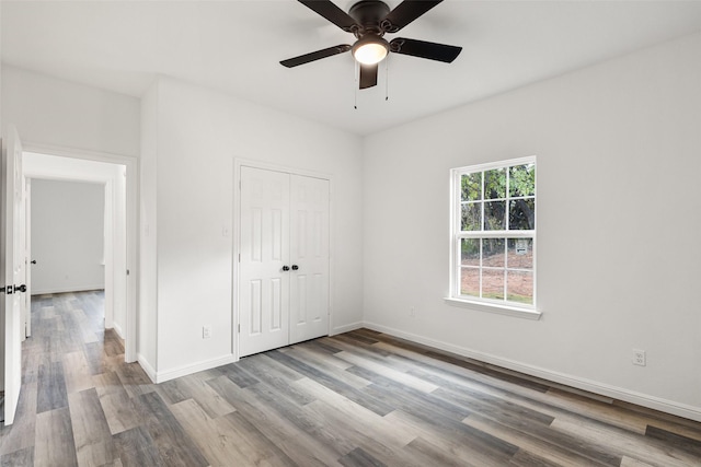 unfurnished bedroom with ceiling fan, light wood-type flooring, and a closet