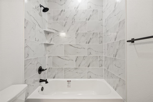 bathroom with tiled shower / bath combo and toilet