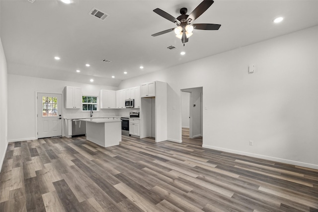 kitchen featuring hardwood / wood-style floors, white cabinets, ceiling fan, appliances with stainless steel finishes, and a kitchen island