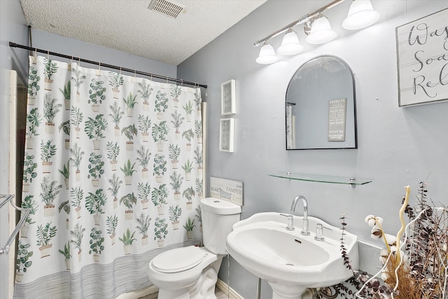 bathroom with sink, a textured ceiling, toilet, and walk in shower