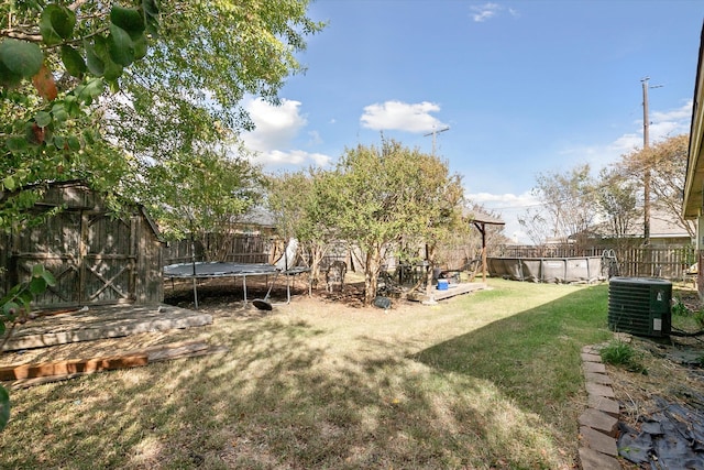 view of yard with central AC unit and a trampoline