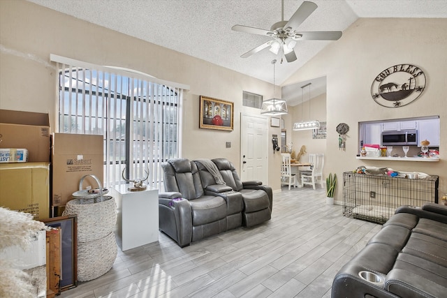 living room featuring hardwood / wood-style floors, a textured ceiling, high vaulted ceiling, and ceiling fan