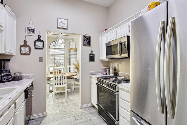 kitchen with appliances with stainless steel finishes, light hardwood / wood-style flooring, and white cabinetry