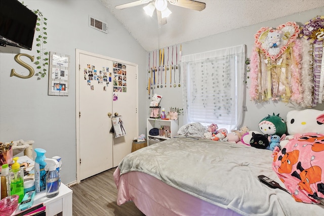 bedroom with vaulted ceiling, a textured ceiling, light wood-type flooring, and ceiling fan