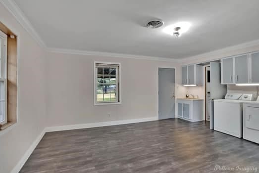 clothes washing area featuring dark wood-type flooring, crown molding, cabinets, and washer and clothes dryer